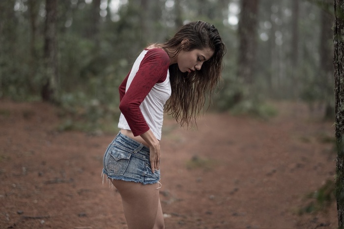 Woman in jean shorts and t-shirt in forest during rain