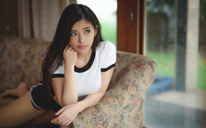 Asian woman in white t-shirt and shorts on couch