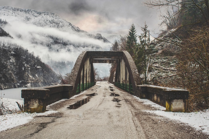 Concrete bridge over a snowy mountain landscape