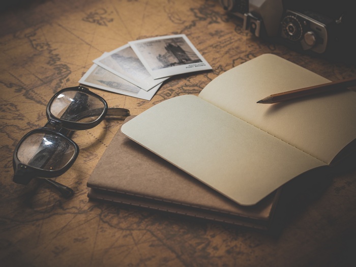 Vintage camera, glasses, notebook, and photos on a map
