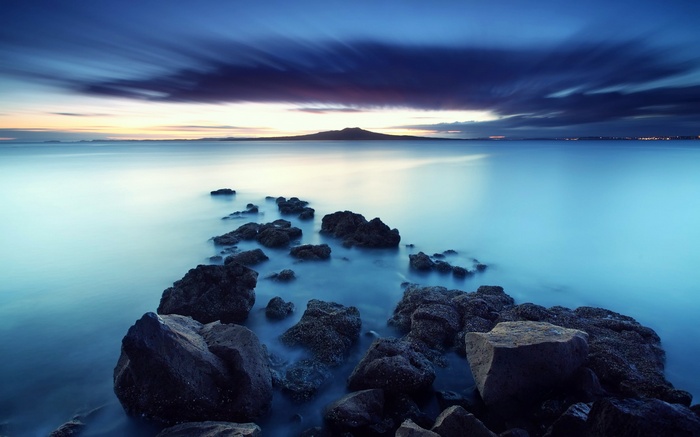 Rocky coastline at dusk with distant mountain