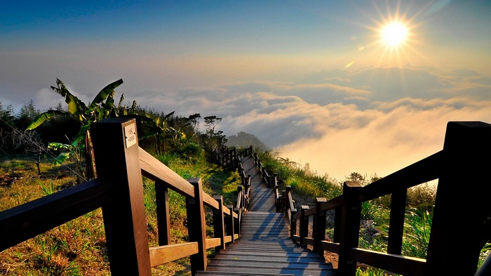 Wooden stairs leading to a sea of clouds at sunrise