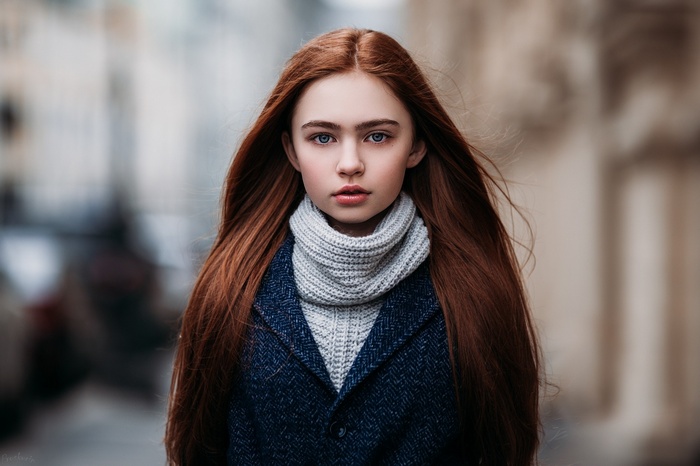 Young woman with long red hair wearing a coat and scarf