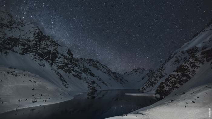 Snowy mountains and lake under a starry night sky