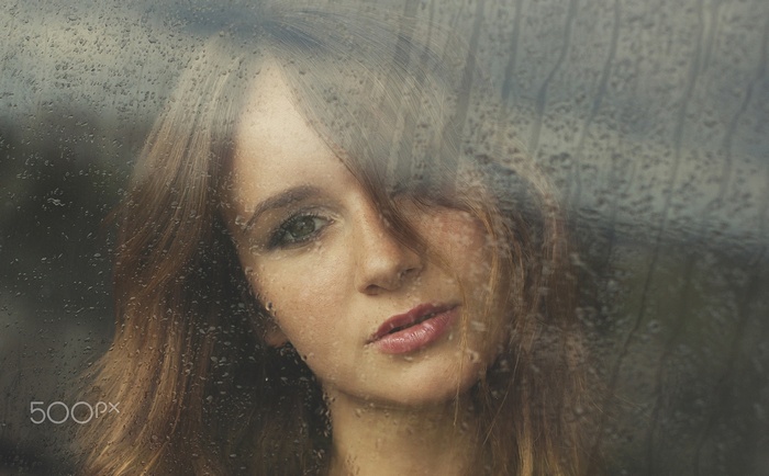 Woman looking through a rain-streaked window