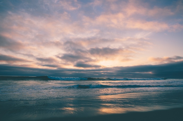Ocean waves at sunset with clouds