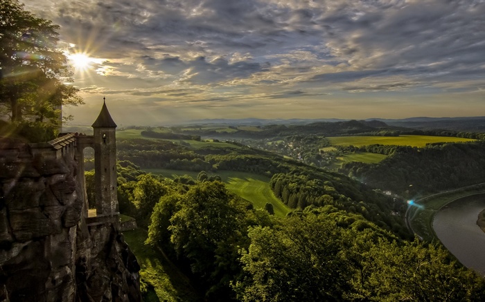 Castle tower on a cliff overlooking a river valley at sunset