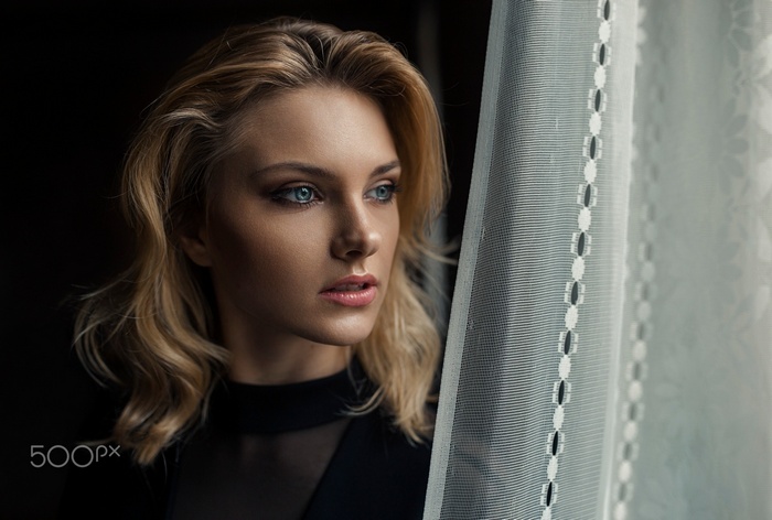 Woman with blonde hair looking out a window