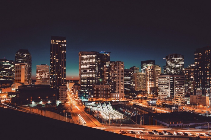 Cityscape at night with illuminated skyscrapers and traffic trails