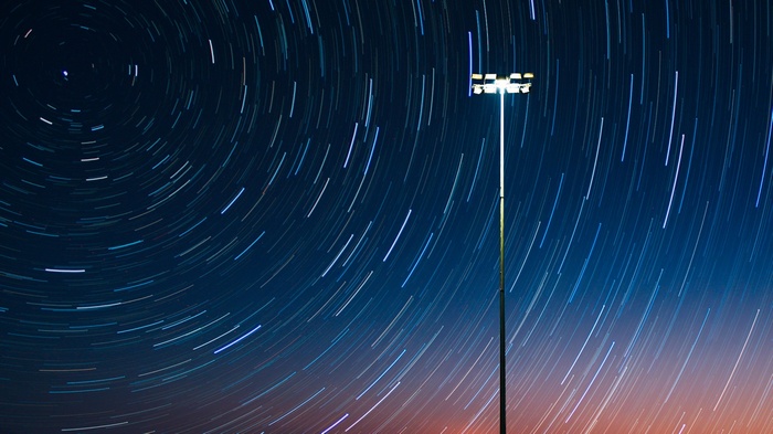 Star trails over a street light at night