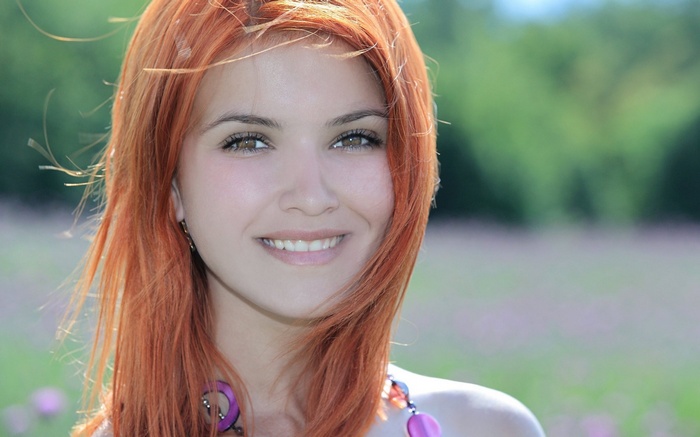 Young woman with red hair smiling outdoors