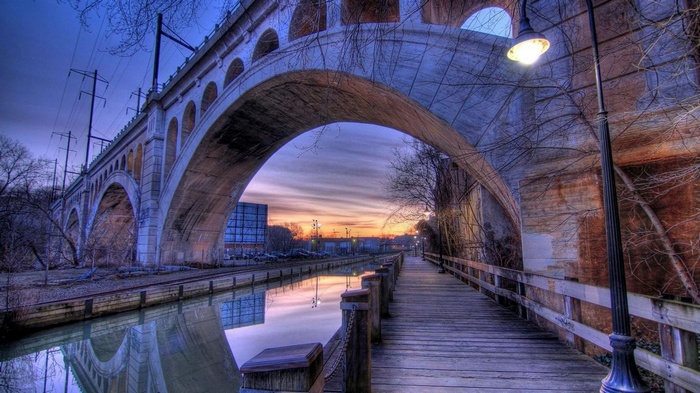 Bridge over canal at sunset with boardwalk and street light
