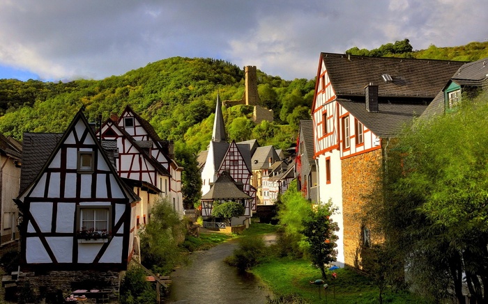 Half-timbered houses and church in a German village with ruins on a hill