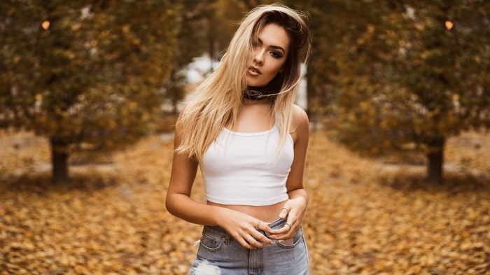 Woman in white crop top and denim shorts in autumn park