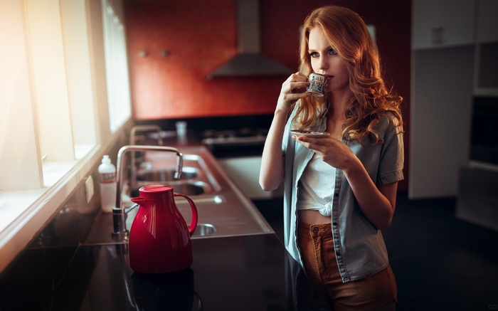 Redhead woman drinking coffee in a modern kitchen