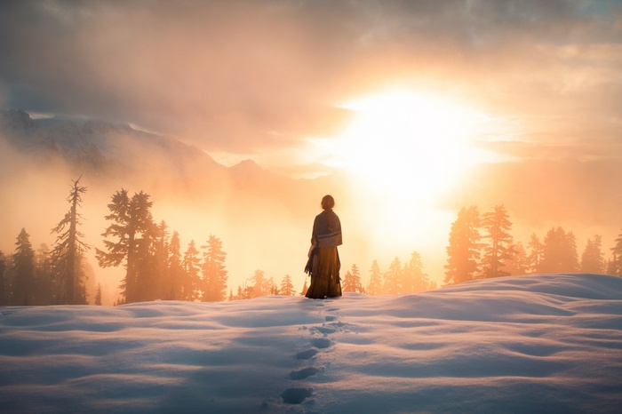 Person in yellow standing in snow at sunrise