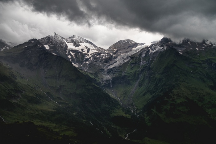 Snow-capped mountains under dark clouds