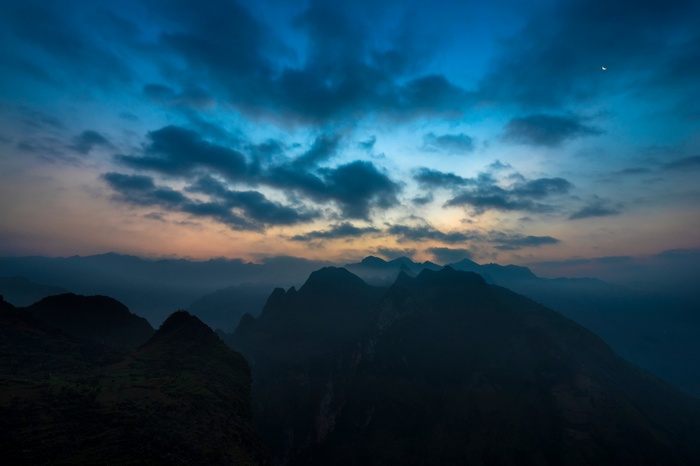 Mountain range at dusk with clouds and moon