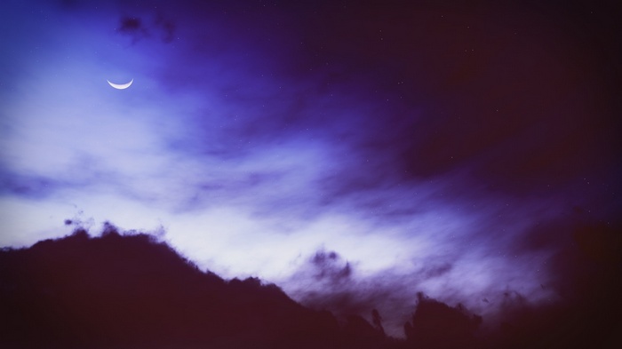 Crescent moon in a cloudy night sky