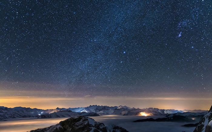 Starry night sky over misty mountains