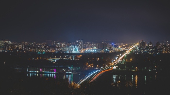 Cityscape at night with light trails over a bridge