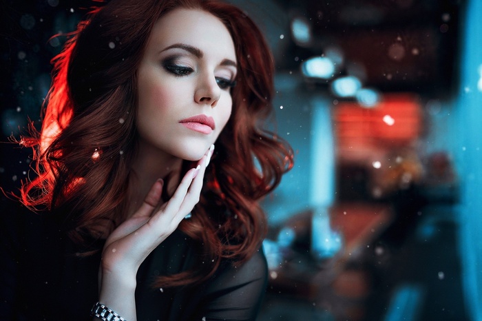Woman with auburn hair and dramatic makeup