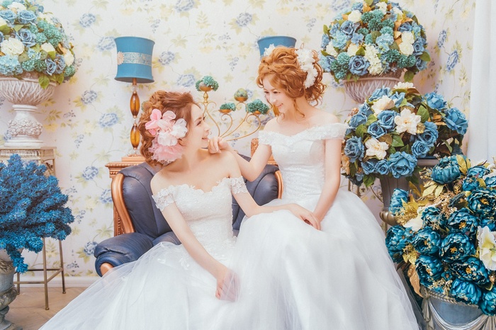 Two Asian women in wedding dresses with flowers