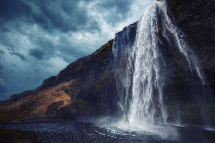 Waterfall cascading down a rocky cliff under an overcast sky