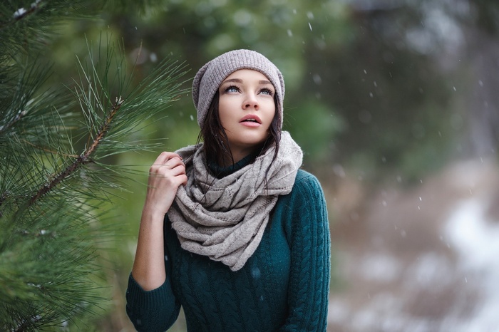 Portrait of a woman in a sweater and scarf outdoors in snow