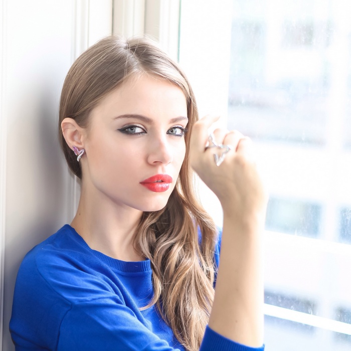 Xenia Tchoumitcheva wearing a blue sweater and jewelry