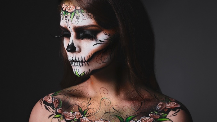 Woman with skull face paint and floral body art