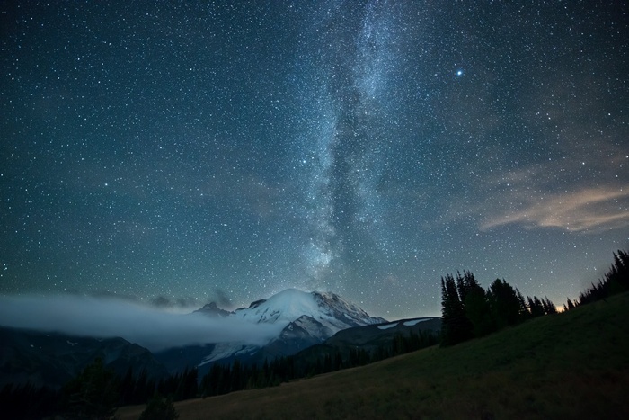 Milky Way over snowy mountain peak with clouds
