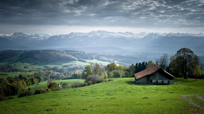 Barn in a green landscape with mountains in the background