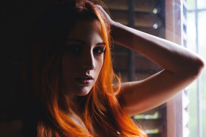 Portrait of a redhead woman with hands on head