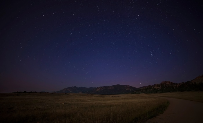 Night sky over mountains and a field