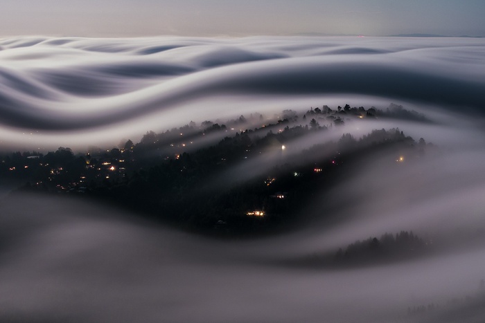 Cityscape shrouded in rolling fog at dusk