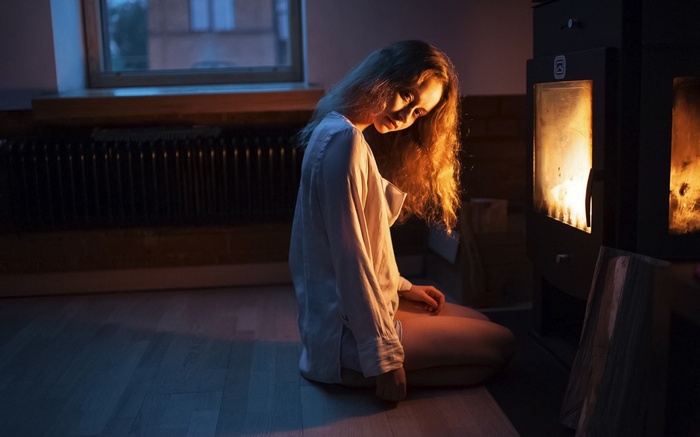 Woman sitting by a fireplace