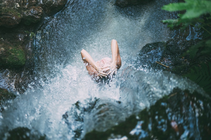 Woman bathing in a waterfall surrounded by nature