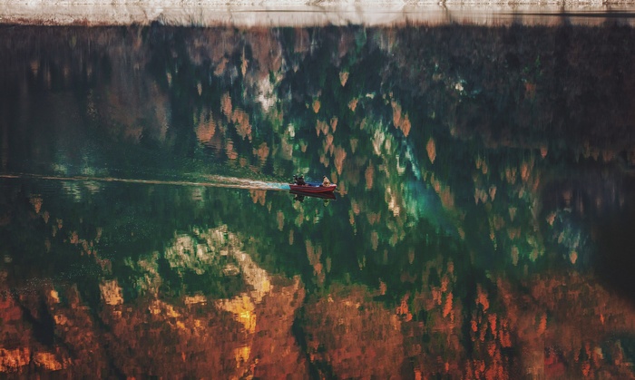 Boat on a reflective lake with autumn foliage