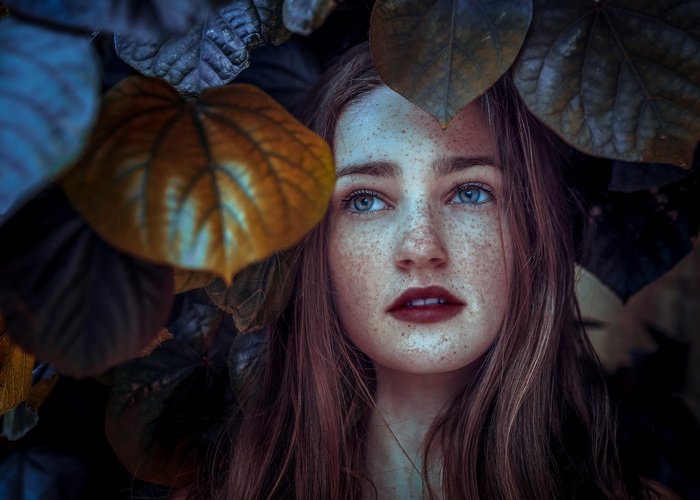 Woman with freckles surrounded by leaves