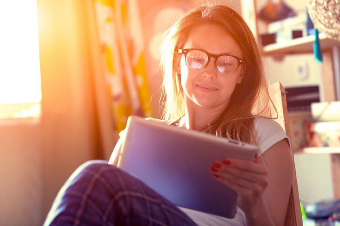 Woman with glasses using a tablet in sunlight