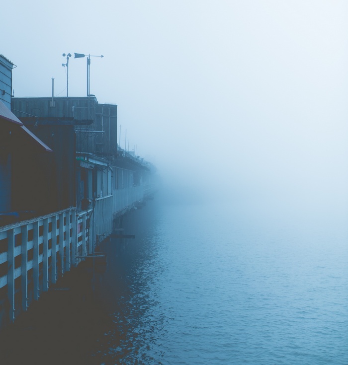 Buildings on a pier in the fog over the sea