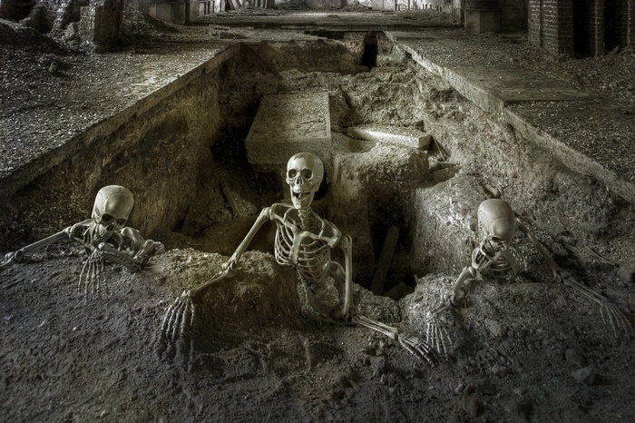 Skeletons emerging from a tomb