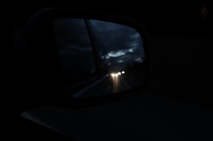 Car side mirror reflecting headlights at night