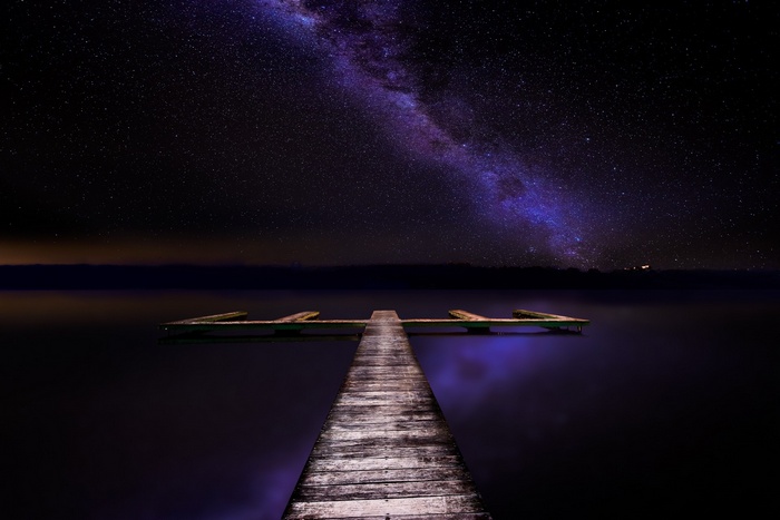 Milky Way over a wooden dock on a lake at night