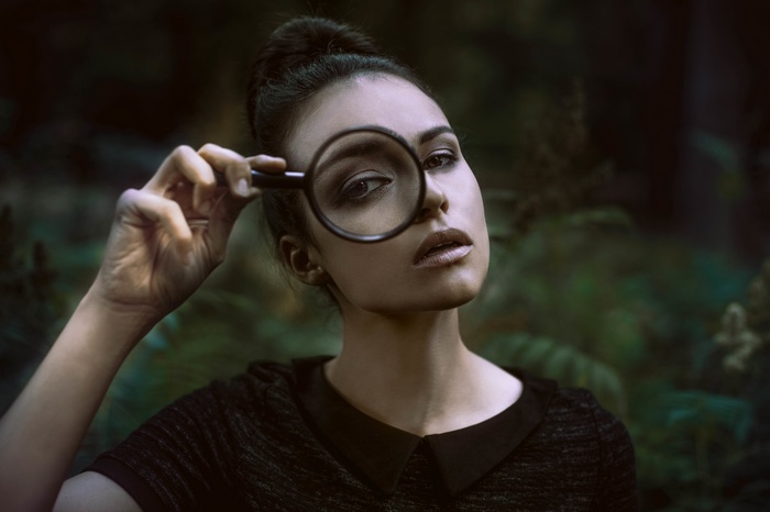 Woman looking through a magnifying glass outdoors