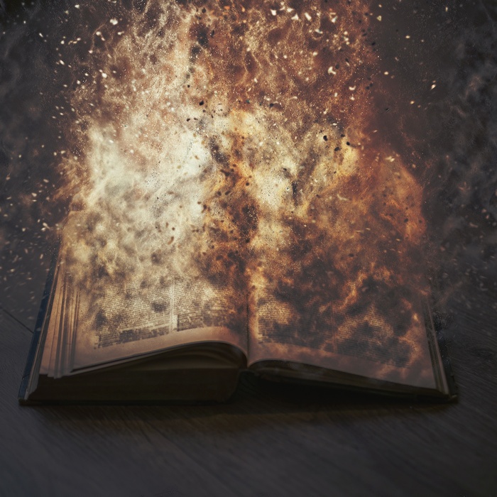 Open book exploding into flames and particles