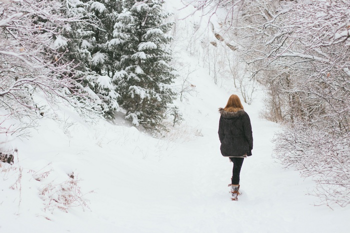 Woman walking on a snowy path in winter forest