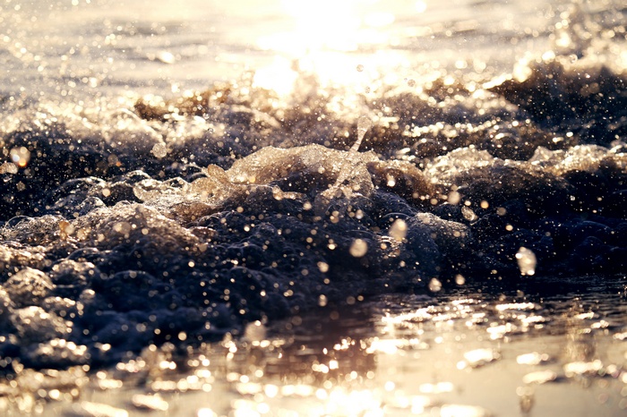 Sunlight on ocean waves crashing on a beach