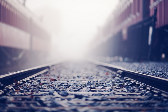 Train tracks disappearing into fog with trains on either side